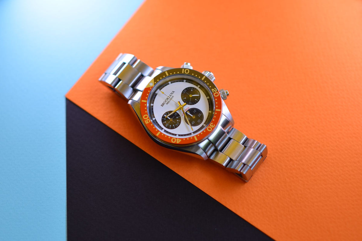 Elegant silver chronograph watch with vibrant dial on a geometric colorful background.