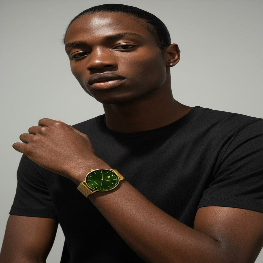 Man wearing a black shirt and yellow gold advance envy 40mm watch with a green face on a gray background