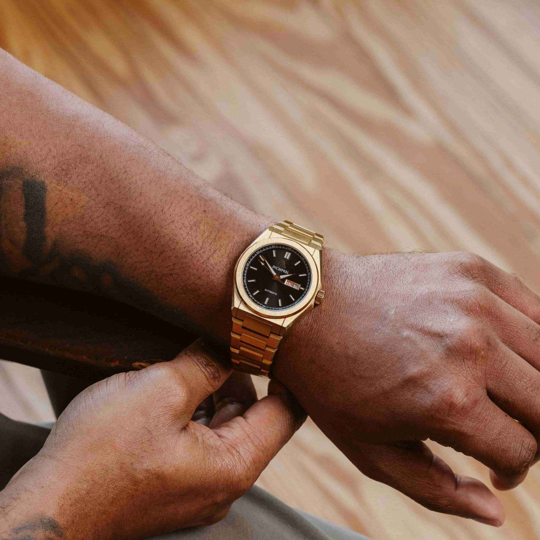 Person adjusting a gold watch on their wrist with a blurred background