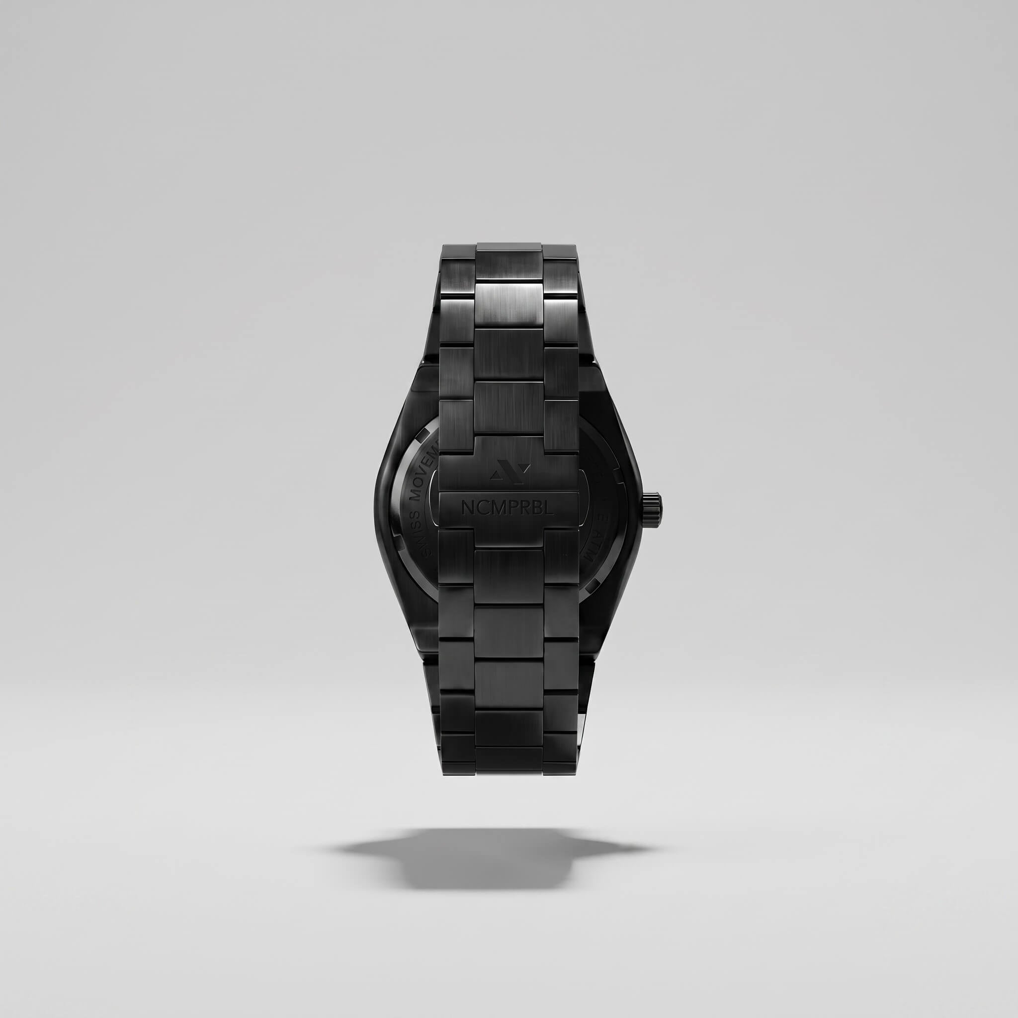 A black stainless steel watch with a matching link bracelet, shown from the back floating against a light gray studio background.