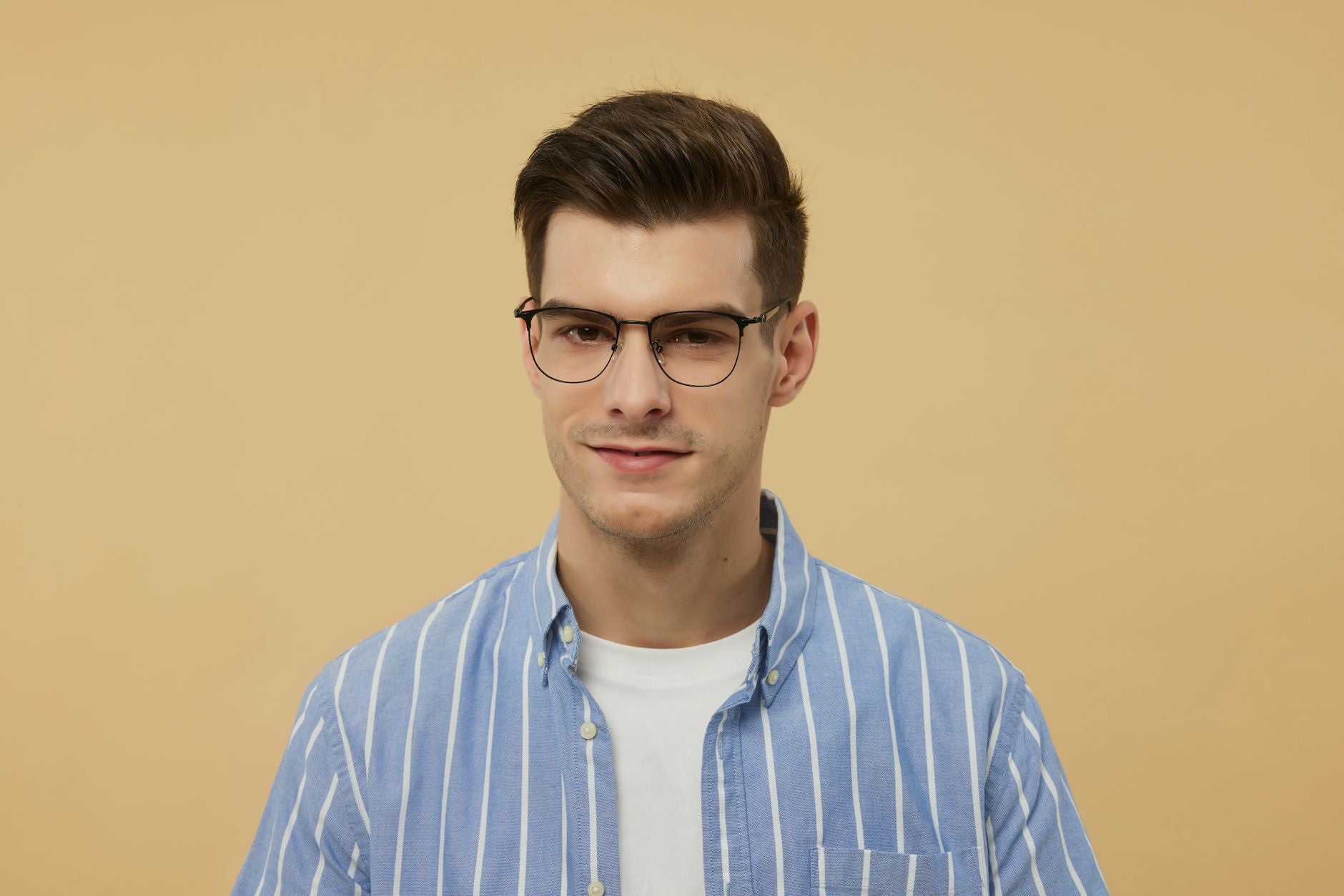 Portrait of a young man wearing stylish eyeglasses and a blue striped shirt.