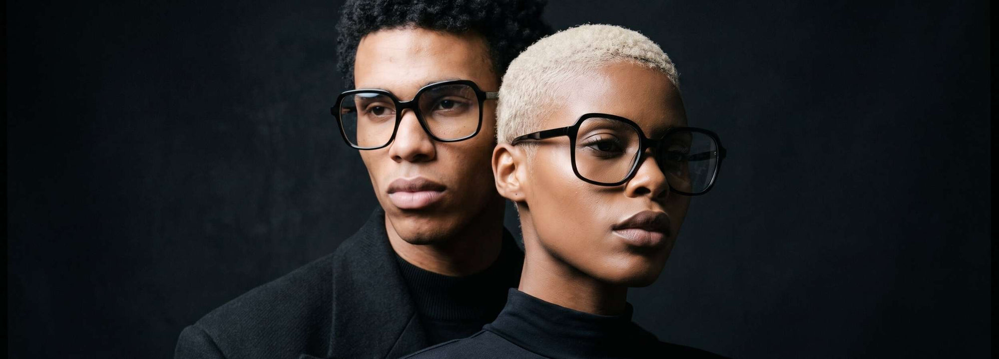 Two models wearing NCMPRBL Axis flat top acetate eyeglasses in a dark studio