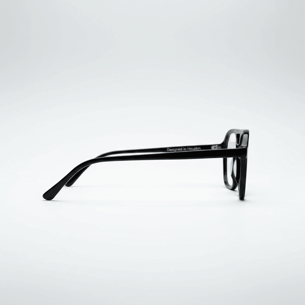 A pair of black square-frame eyeglasses shown in side profile on a clean white studio background. 'Designed in Houston' is printed in white on the temple arm.