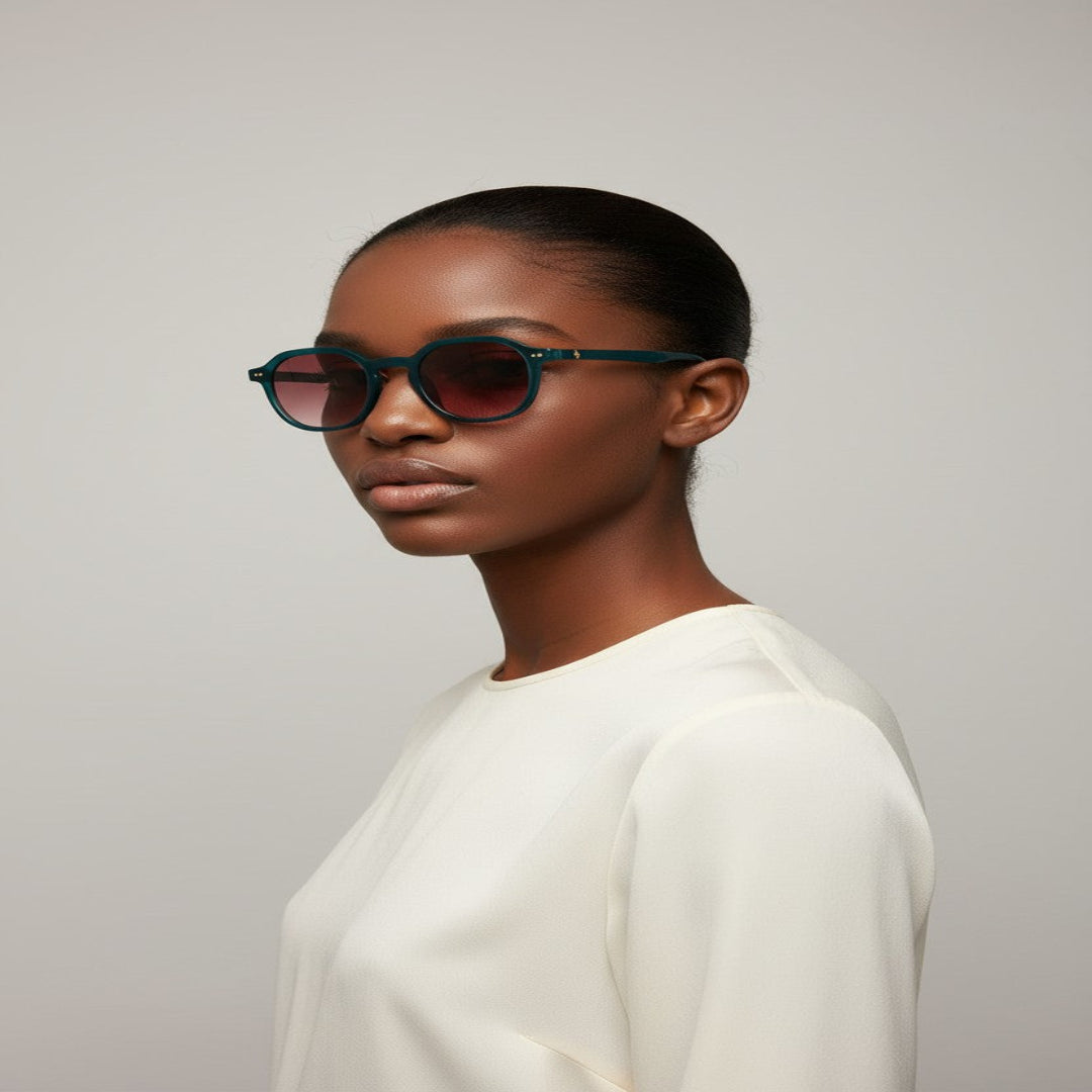 Woman wearing manifest geometric eyeglasses with dark ruby red sunglass tint against a plain background